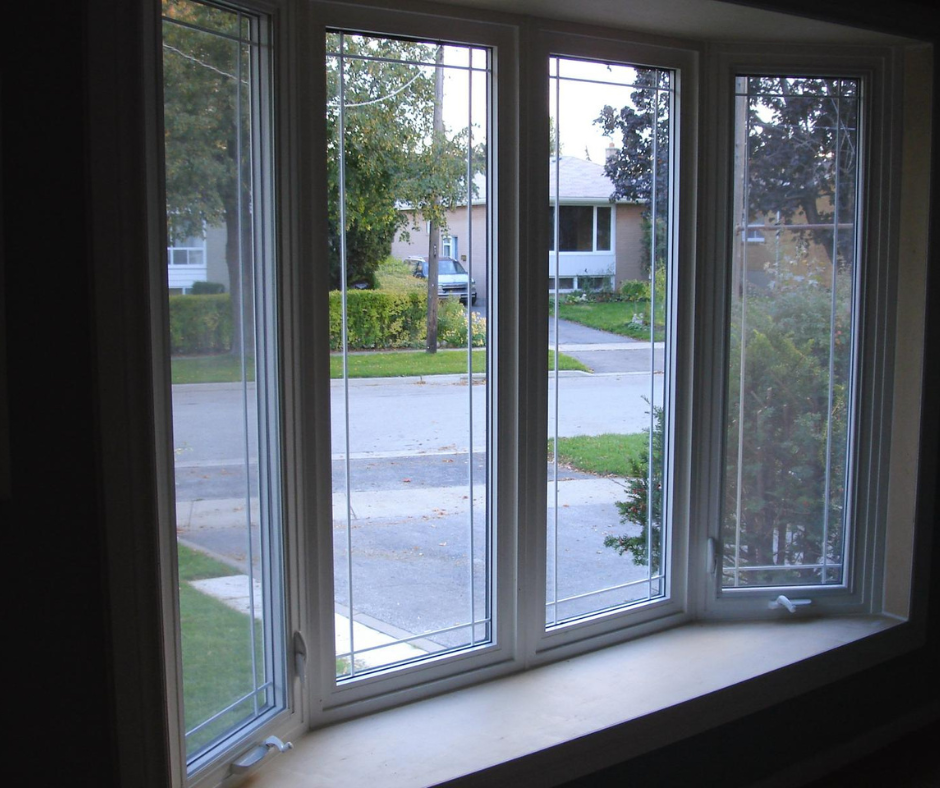Angled interior bay window with white vinyl frames, decorative glass lines, and a wide window ledge