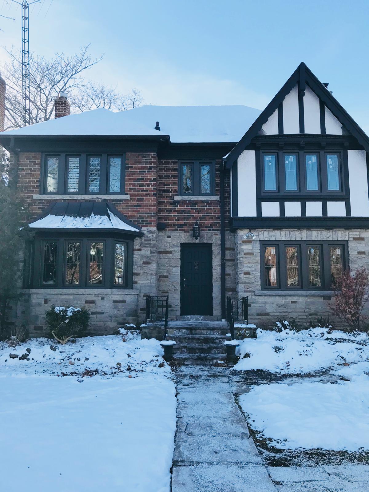 Front bay-style bow window projection with black frames on a brick-and-stone home facade.