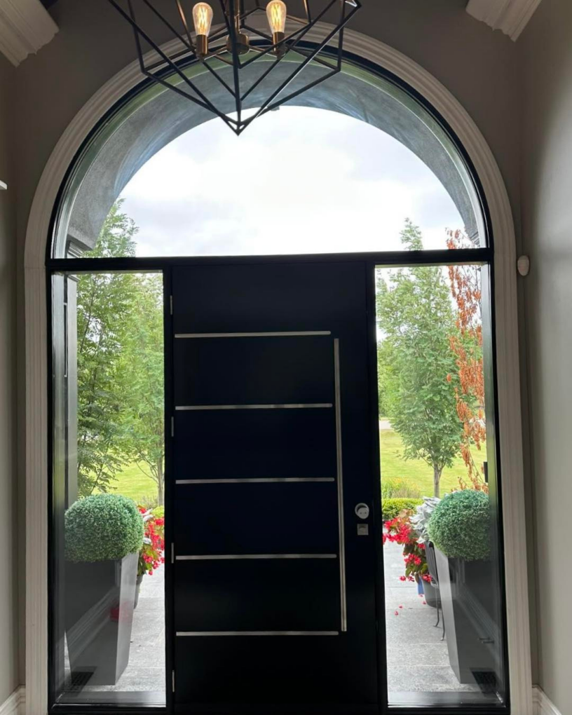 Interior view of single arched front door with large glass transom and clear sidelites opening to the front yard