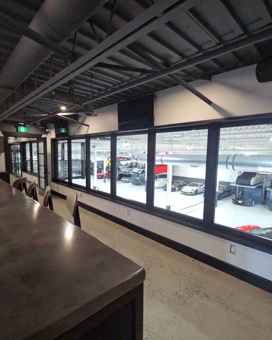 Industrial-style horizontal picture windows in a professional office providing a clear view of a luxury car showroom.