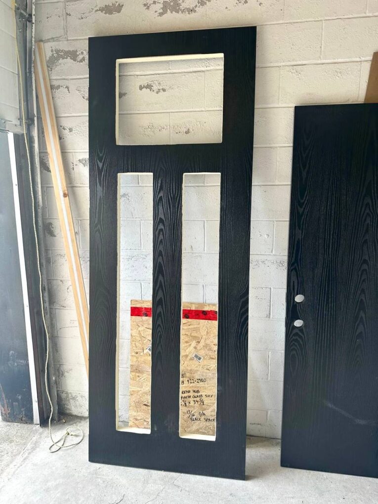 Fiberglass double front doors in production with tall proportions and modern glass design.