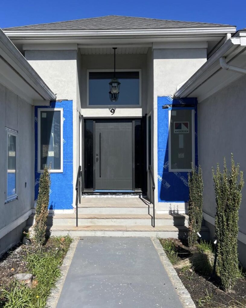 Custom fiberglass entry doors with sidelights for a home in Massachusetts with a modern slab design and long pull bar.