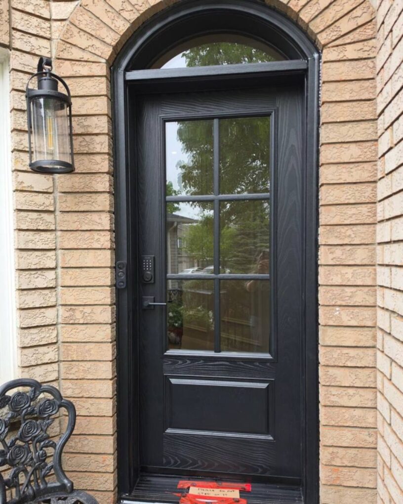 Arched fiberglass entry door in Oakville with a black finish and large grid glass insert