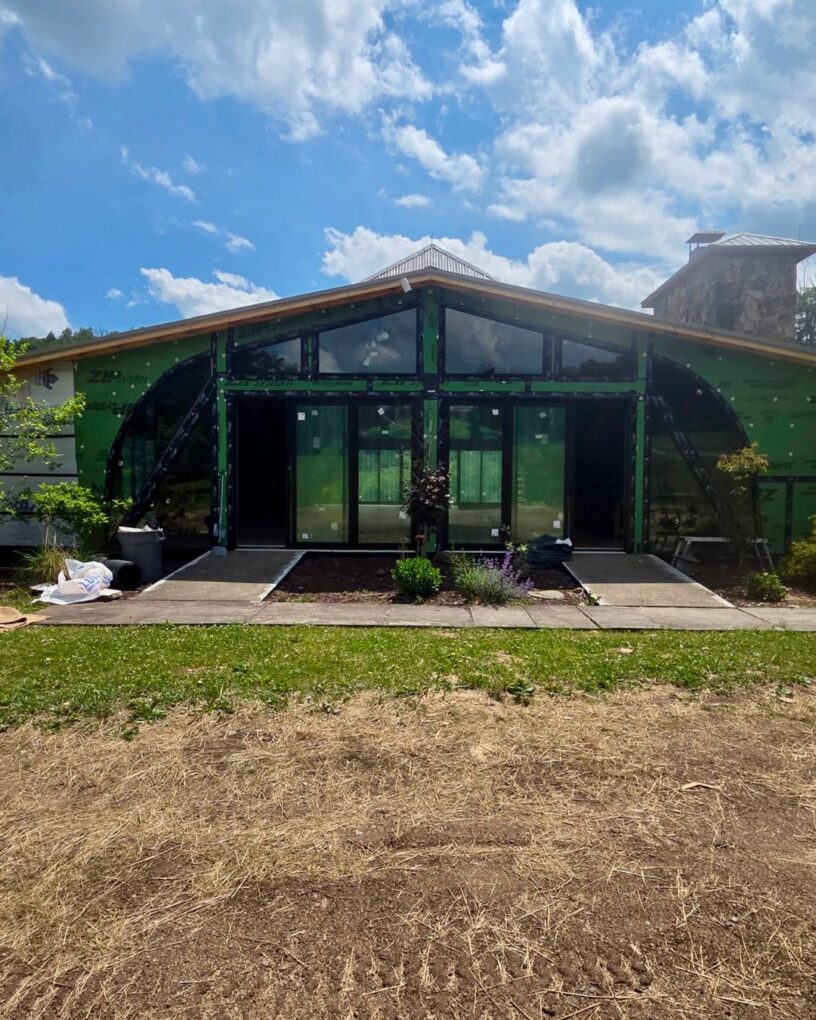 Full exterior view of custom shaped windows and stacked sliding doors facing the deck.
