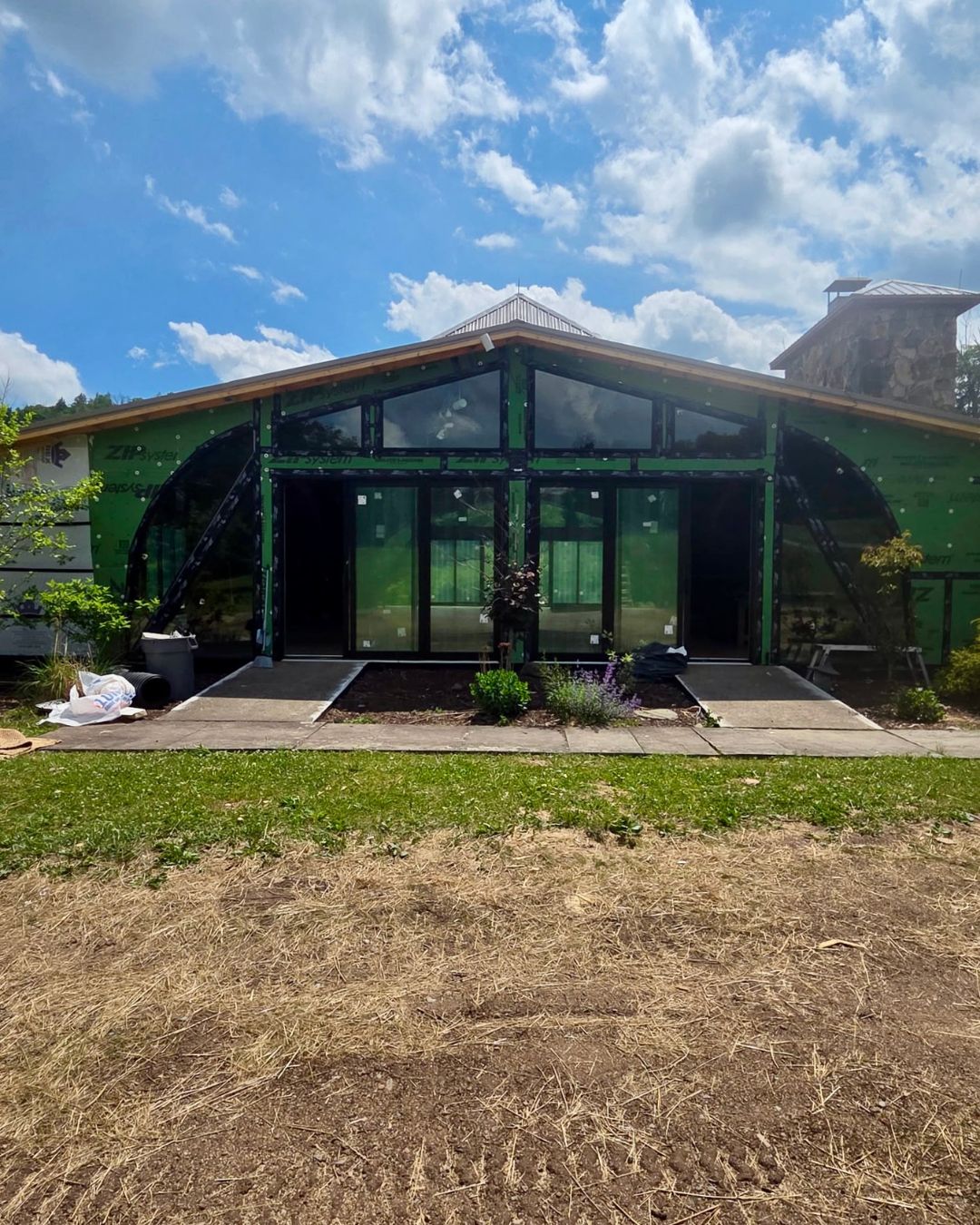 Full exterior view of custom shaped windows and stacked sliding doors facing the deck.