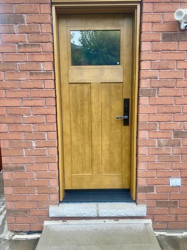 Stained wood-grain fiberglass entry door with a glass insert, black hardware, and multipoint lock, installed in Bradford, Ontario.