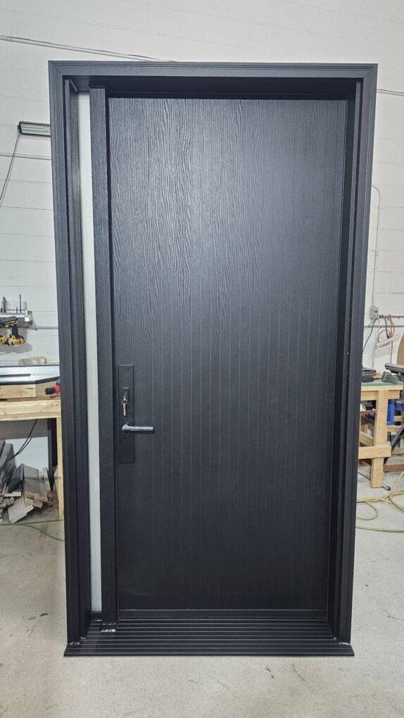 Black fiberglass front door with narrow glass sidelight and woodgrain finish